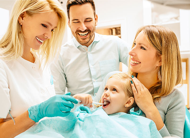 Female dentist with little girl and smiling parents